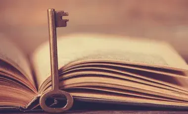 An old key leans on the spine of an open book