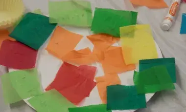 Paper plater with squares of colored tissue paper glued onto it.