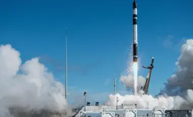 rocket blasting off with smoke and a blue sky