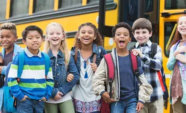 kids with backpacks in front of a school bus