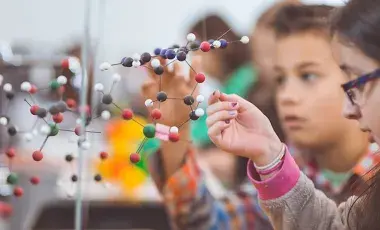 Several children are looking at a 3D model of atoms. 