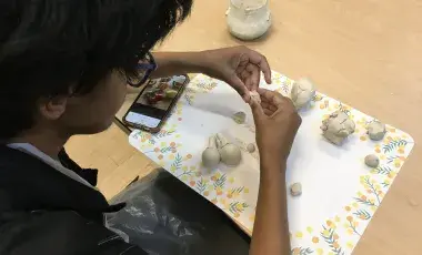 Teen manipulating clay with hands on table