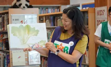 Woman reading a picture book to children in a library