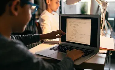 A boy uses his laptop for computer coding