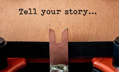 Piece of paper in a typewriter that says Tell your story