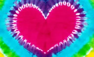 A tie-dye of a pink heart surrounded by the colors of the rainbow.
