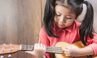 A young girl playing a ukulele.