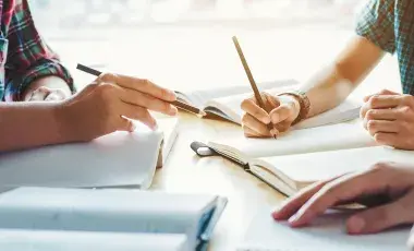 Three adults writing on a notebook.