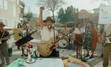 Zosimo Quibilan holding a guitar with his fist in the air.