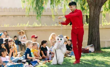Man with marionette with a crowd of kids.  