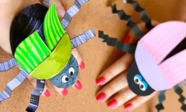 Beetle crafts, wrapped around hands, created with black, pink and green paper.