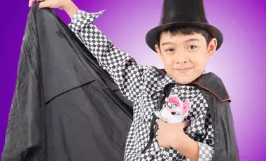 young boy in black cape and tall hat holding a stuffed bunny 