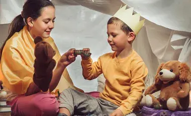 two children play in a tent with puppets
