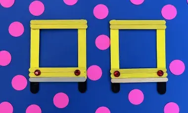 Handmade popsicle stick picture frame colored in yellow, gray, and blac
