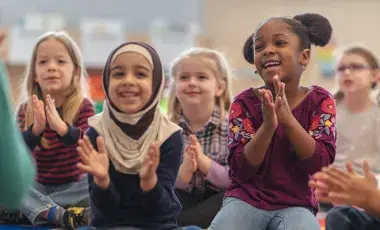 Kids sitting on the rug clapping
