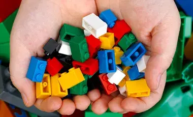 Two hands hold multicolored Lego blocks