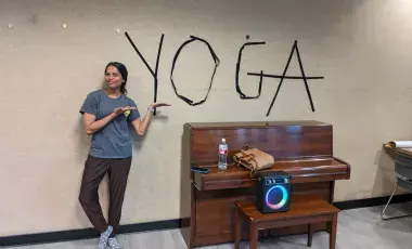 Person pointing to the word "Yoga" on the wall.