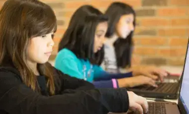 Three students sitting, using laptop computers.