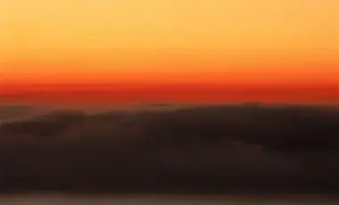 Sky during sunrise featuring a gradient of orange and dark clouds