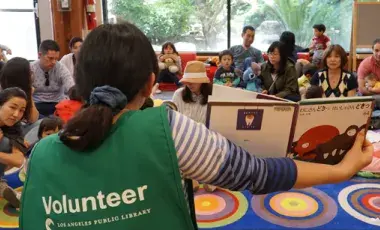 Star volunteer reading to a group of adults with children.