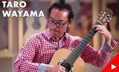 man in glasses playing a guitar 