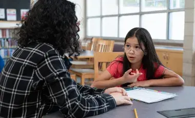 student talking to a tutor in a library