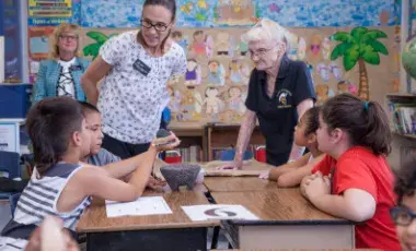 Two teachers engage with a table full of students.