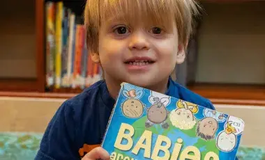 Toddler holding a book.