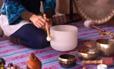 Close up image of a woman's hands playing a quartz singing bowl