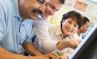Adult students learning computer skills in a classroom.