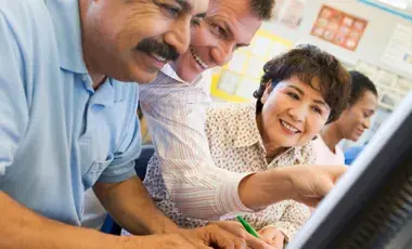 Mature students learning computer skills in a classroom.