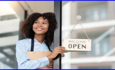 Woman holding an open sign front of a window