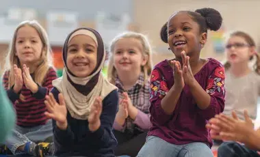 A group of diverse children clapping during story time.