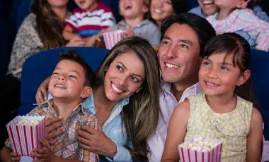 A smiling young family of four watch a movie