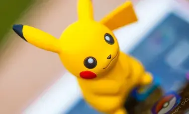 Pikachu figurine on top of a device featuring Pokemon TCG app