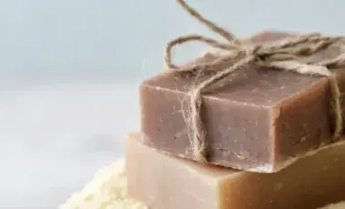 Two bars of soap stacked upon one another. The top bar is decorated with a jute twine bow tie.