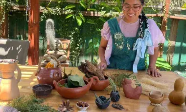 A woman wearing an apron in front of handmade clay objects. 