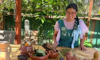An artisan at a workshop table surrounded by clay materials and clay sculpture.