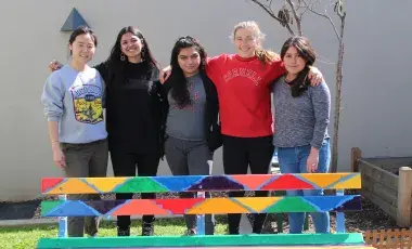 group of teens with a painted bench
