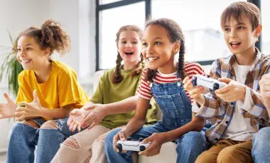 Young people sitting on a couch and playing video games with controllers in their hands.