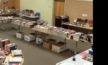 A library with boxes of books and tables of books 