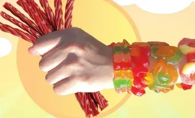A hand holding red licorice wearing several bracelets made with gummy candies