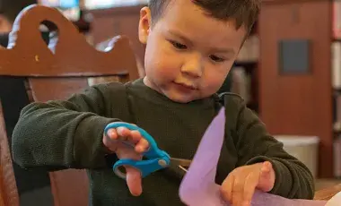Child cutting paper with scissors