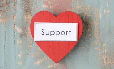 red heart with the word support written in black text