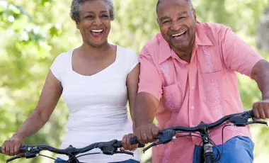  older couple biking with woman wearing a white shirt and man wearing pink shirt