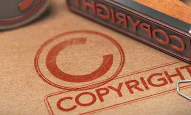 A copyright symbol on a piece of brown paper with a metal stamp placed on top.