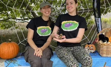 Two girls sitting in front of a spiderweb display