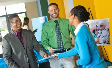Young professional submitting resume to business team at job fair