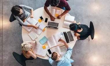 High view of circular table with students studying