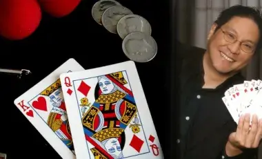 Magic show props alongside magician "Magic Wayne" holding a fanned deck of face cards.
